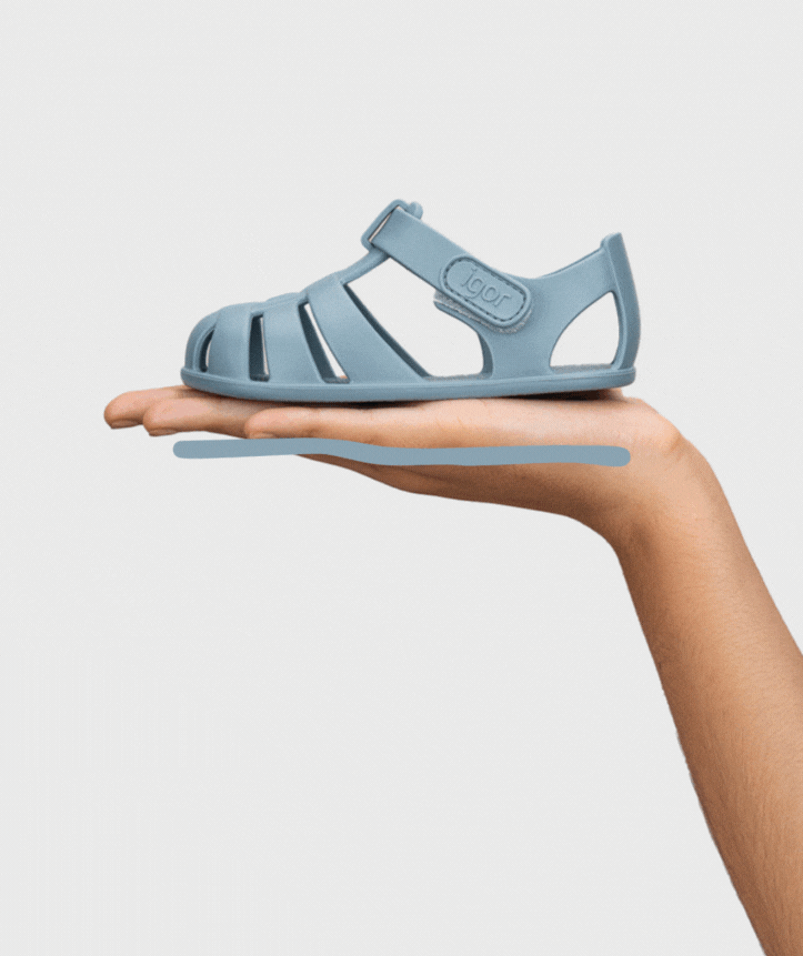 Sandália azul clara em uma mão com fundo branco