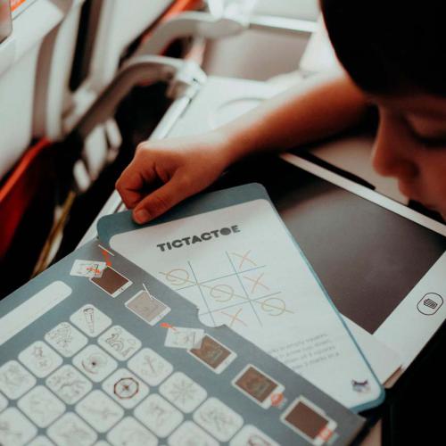 Criança a jogar jogo TICTACTOE em folhas reutilizáveis de plástico