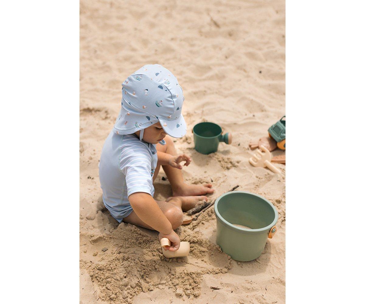 Criança com chapéu azul brincando com balde e utensílios na areia