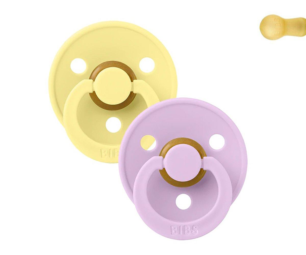Duas chupetas redondas de silicone, uma amarela e outra rosa, com alças e orifícios.