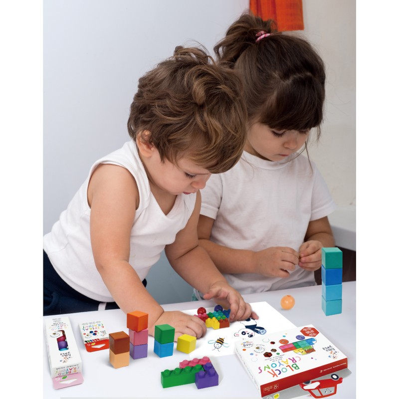 Duas crianças a brincar com blocos de construção coloridos de madeira numa mesa branca