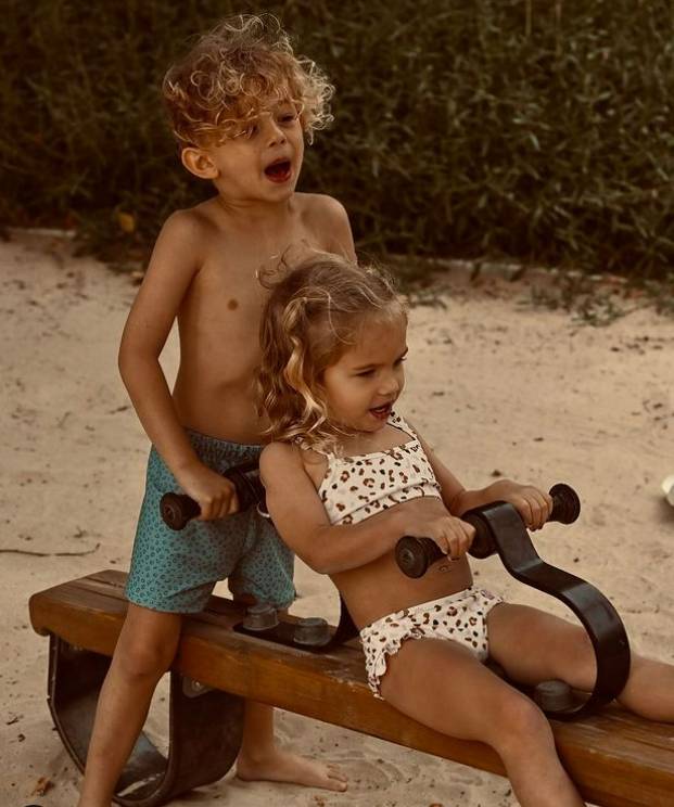 Criança e menina em gangorra de madeira ao ar livre