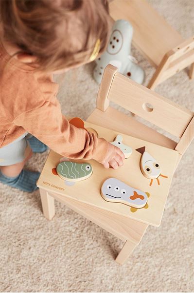 Quebra-cabeça de madeira com peças de animais em cadeira de madeira clara com criança