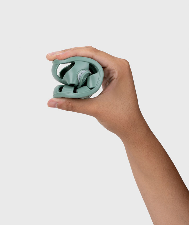 Sapato desportivo verde-água flexível sendo segurado e comprimido por uma mão contra fundo branco