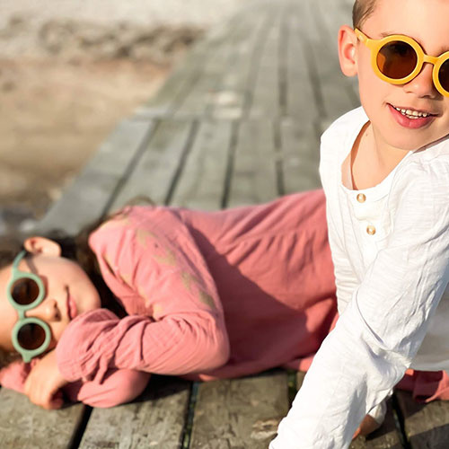 Dois rapazes jovens com óculos de sol coloridos em madeira velha ao ar livre