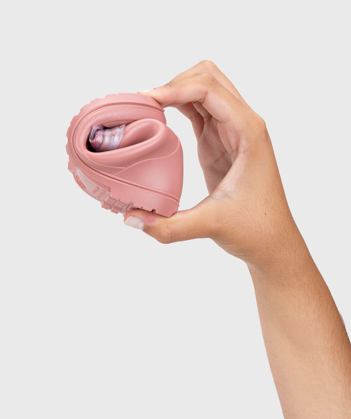 Sapato desportivo cor de rosa dobrado na mão