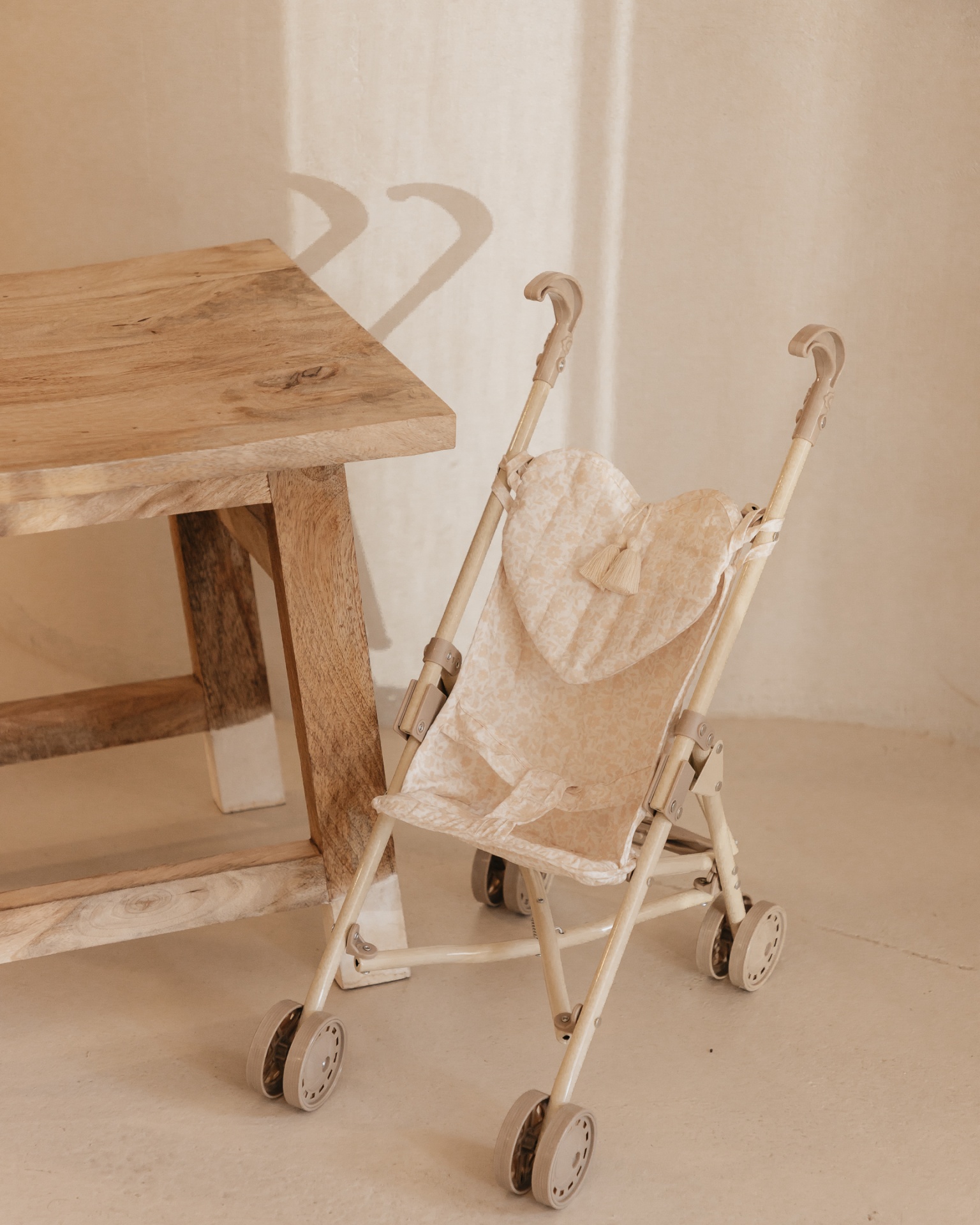 Carrinho de bebé bege com padrão coração junto a mesa de madeira