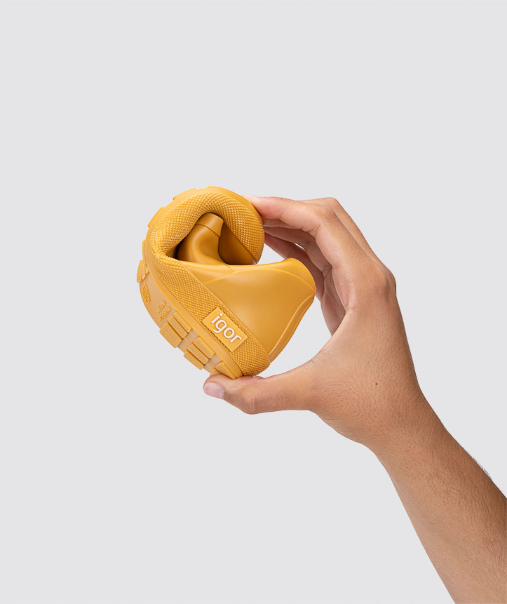 Sapato amarelo mostarda dobrado, com sola tratorada e texto igor na lateral, segurado por mão