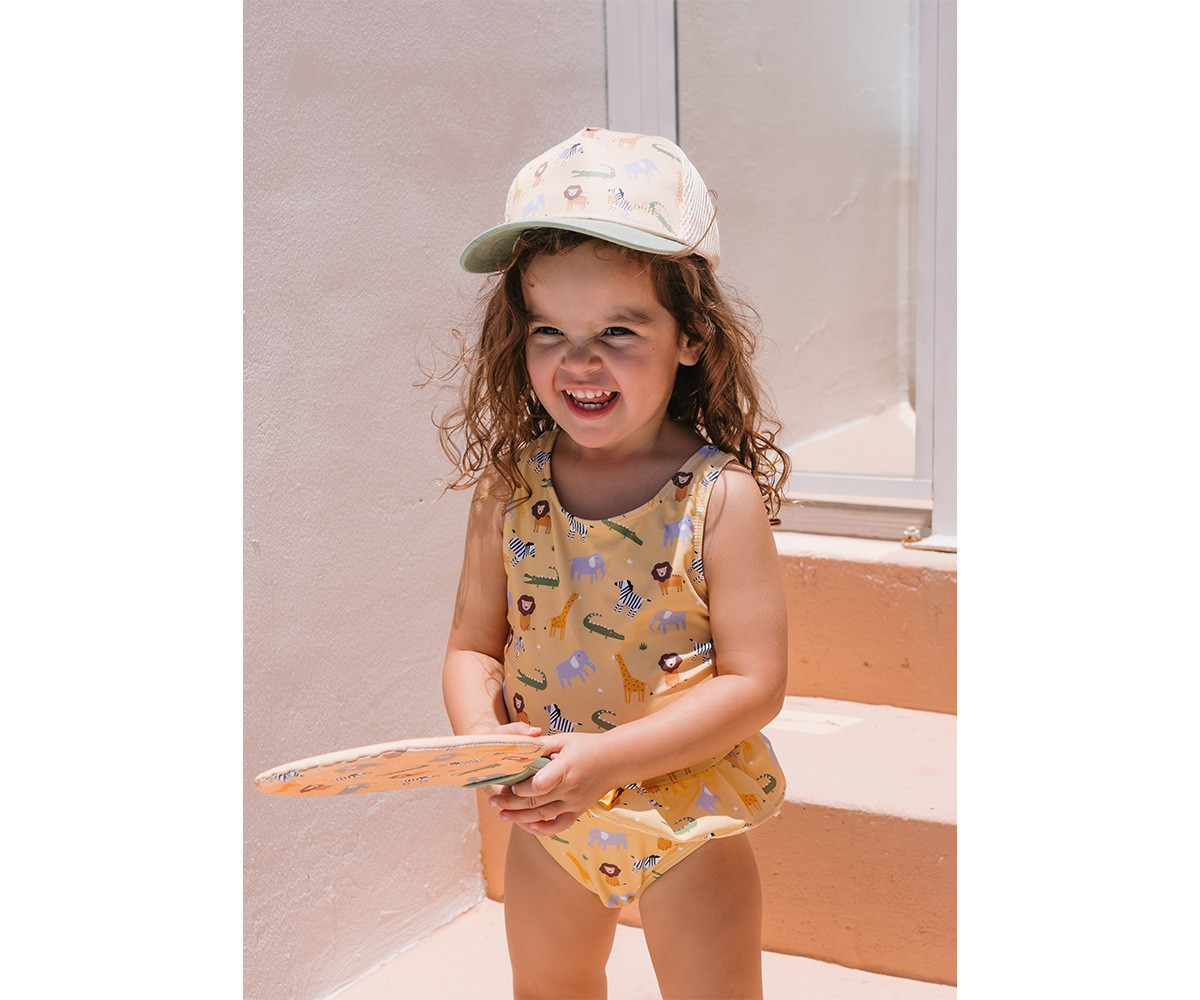 Menina com fato de banho e boné com padrão animal a segurar raquete