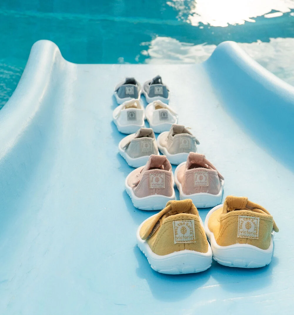 Cinco pares de sapatilhas de lona coloridas numa superfície azul