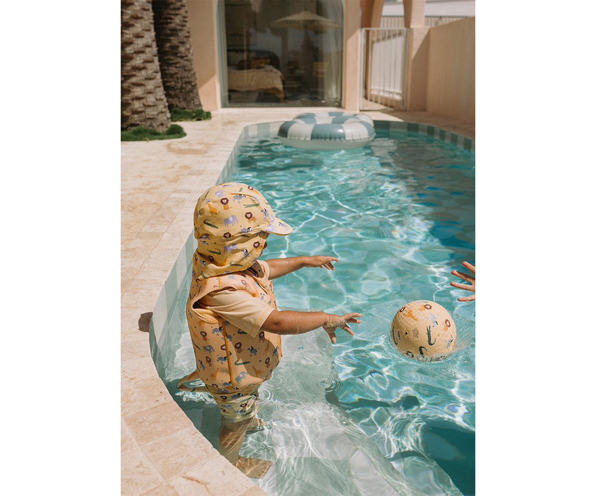 Criança com roupa de banho amarela com padrão de animais a brincar na piscina