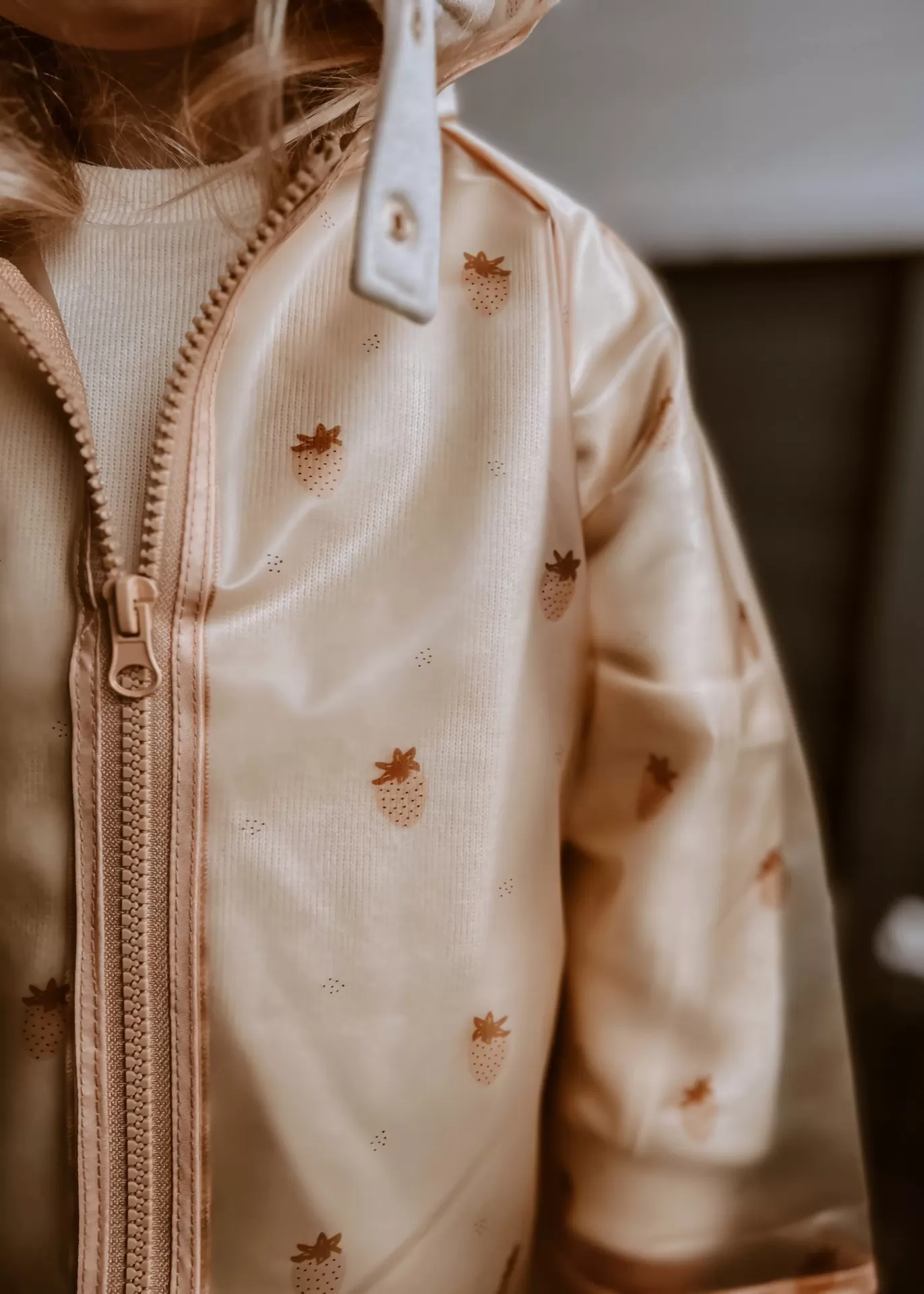 Casaco bege com padrão de morangos pequenos e fecho de correr à frente