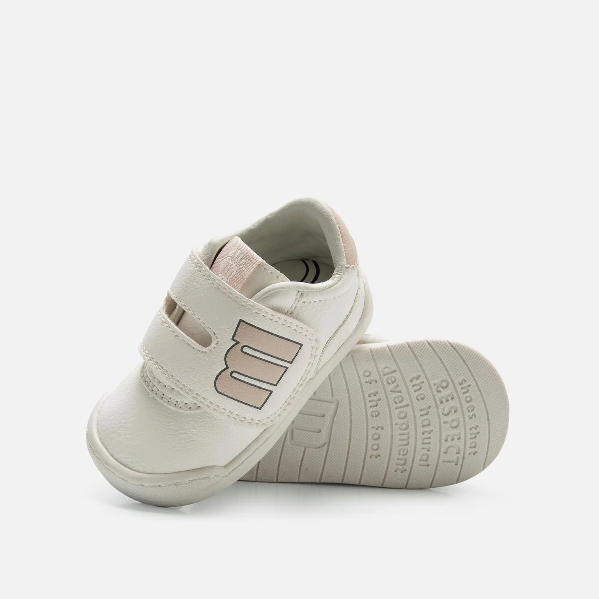 Sapatilhas brancas de criança com fecho de velcro e sola com texto. 