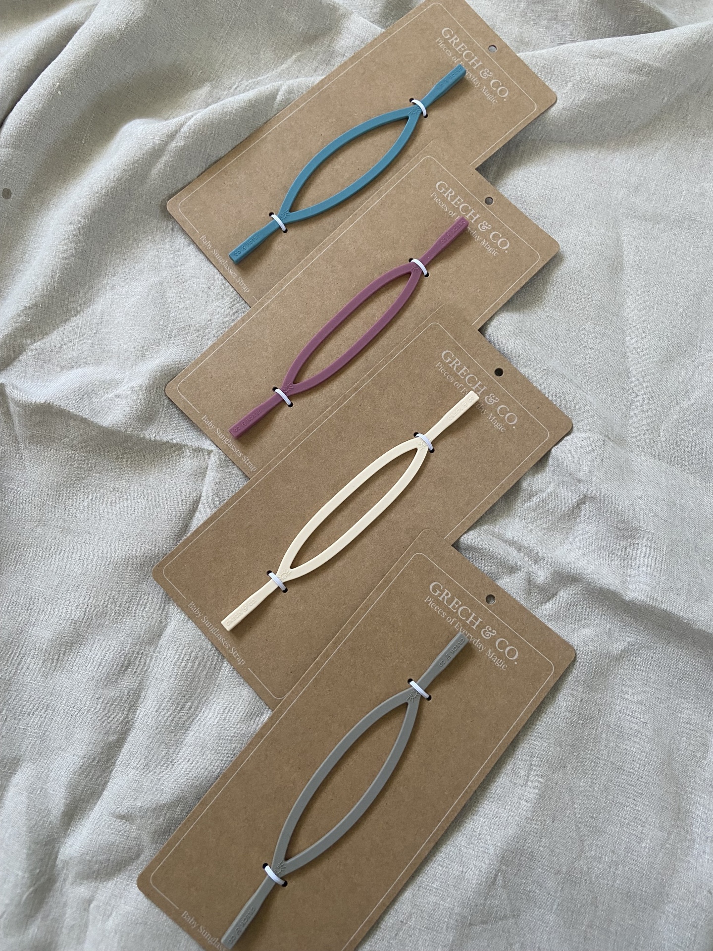 Ganchos de cabelo de metal coloridos em cartões castanhos sobre tecido cinzento claro