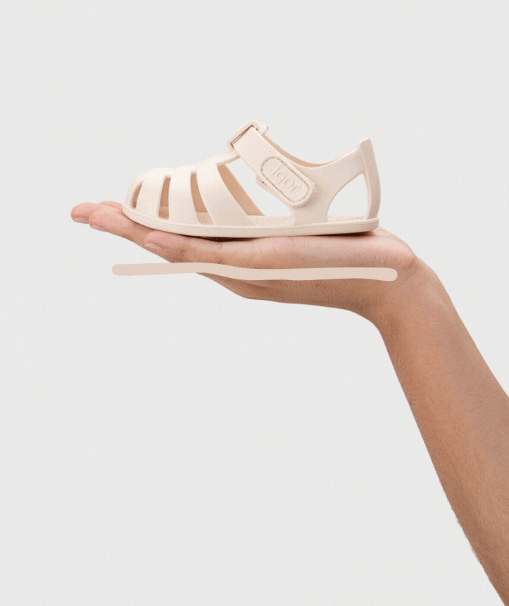 Sandália infantil em plástico bege claro numa mão