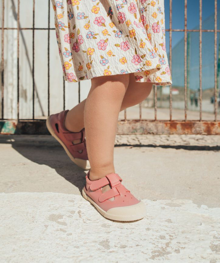 Criança com sapatos cor-de-rosa e vestido florido no exterior