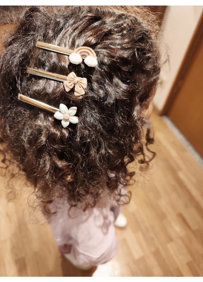 Três presilhas de cabelo decorativas em cabelo cacheado castanho
