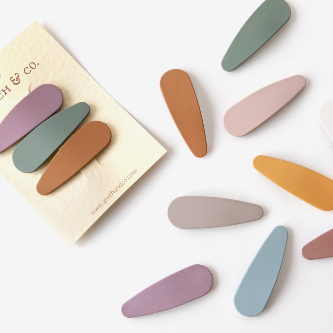 Molas de cabelo coloridas em tons pastel em cartão e sobre superfície branca