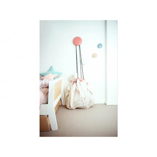 Quarto infantil com cama e saco branco estampado junto a três ganchos coloridos na parede.