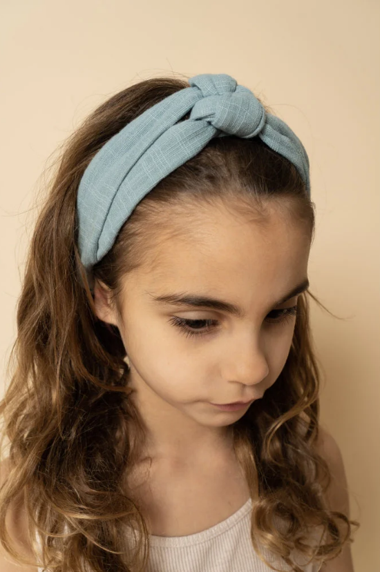 Menina a usar faixa de cabelo azul claro com nó frontal