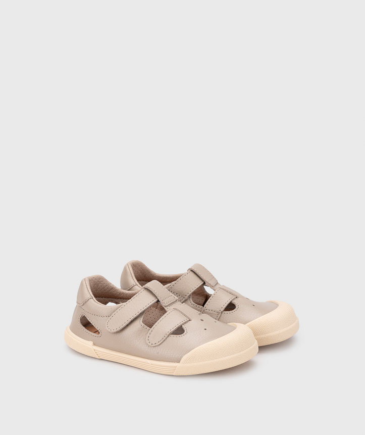 Sapatos infantis em pele bege com sola creme e fecho de velcro.