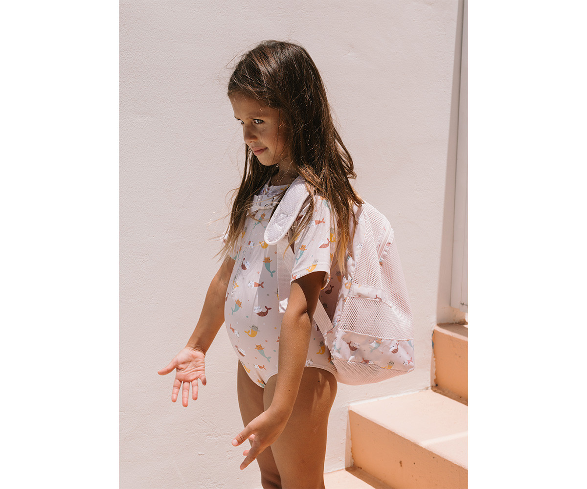 Criança com fato de banho e mochila branca com padrão de peixes