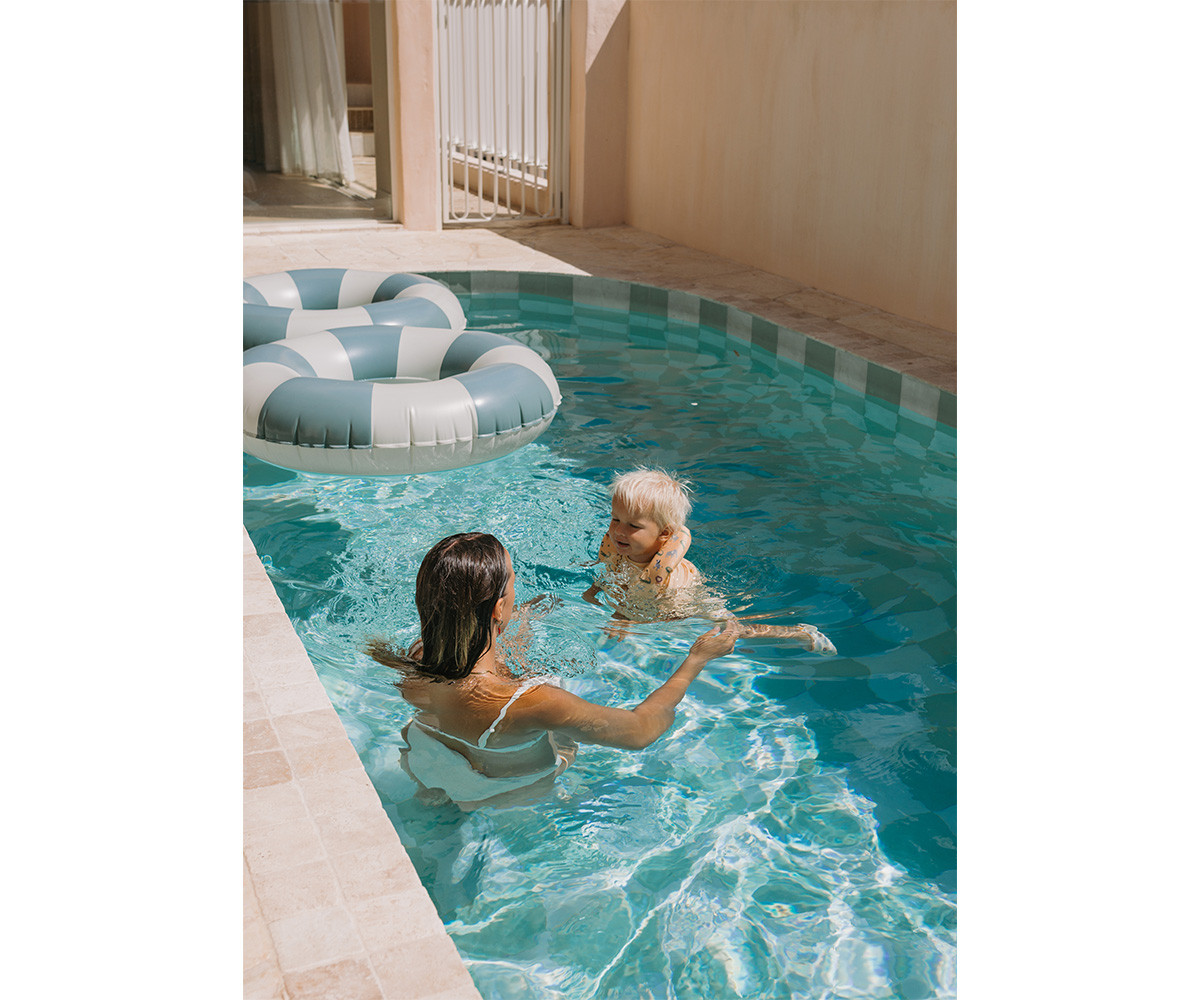 Mulher e criança numa piscina com colchão insuflável às riscas