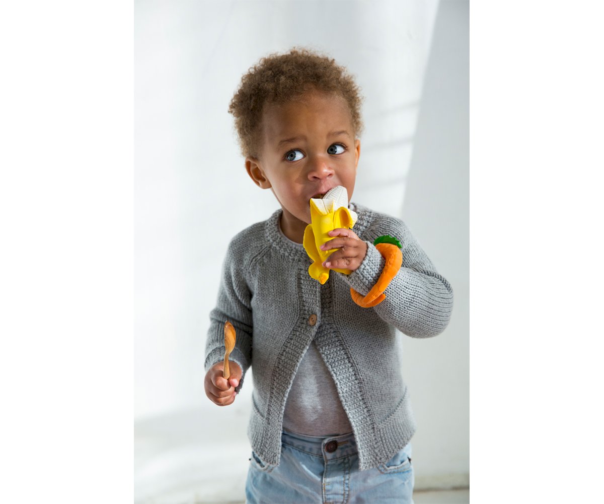 Criança pequena com brinquedo de banana em casa