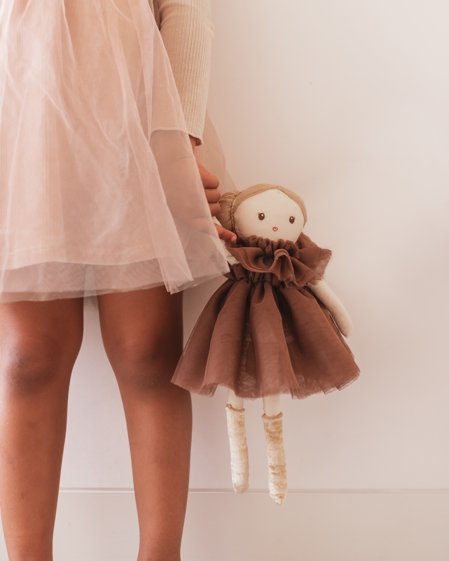 Criança a segurar uma boneca de pano com vestido castanho