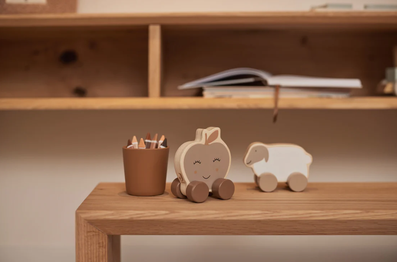 Brinquedos de madeira em tons naturais e castanhos sobre mesa de madeira clara