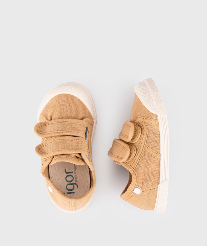 Sapatos infantis castanhos com sola branca e fecho de velcro.