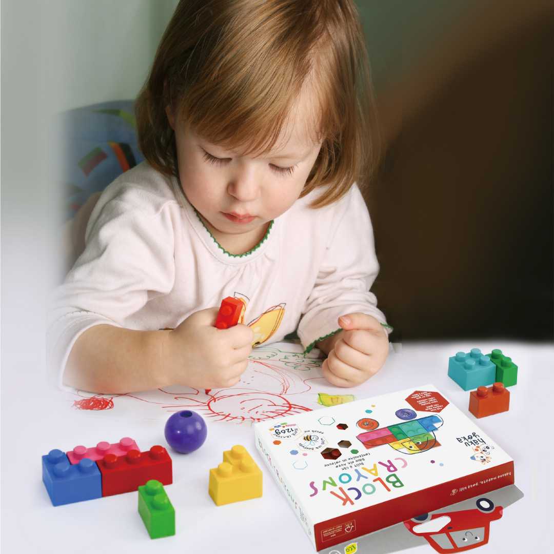 Criança a desenhar com marcador vermelho com blocos de construção coloridos e caixa de brinquedo