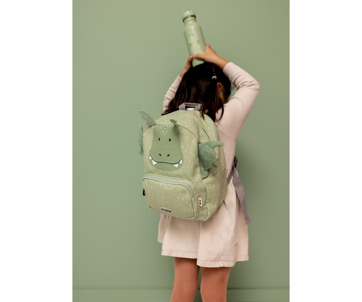 Criança com mochila infantil verde em fundo verde