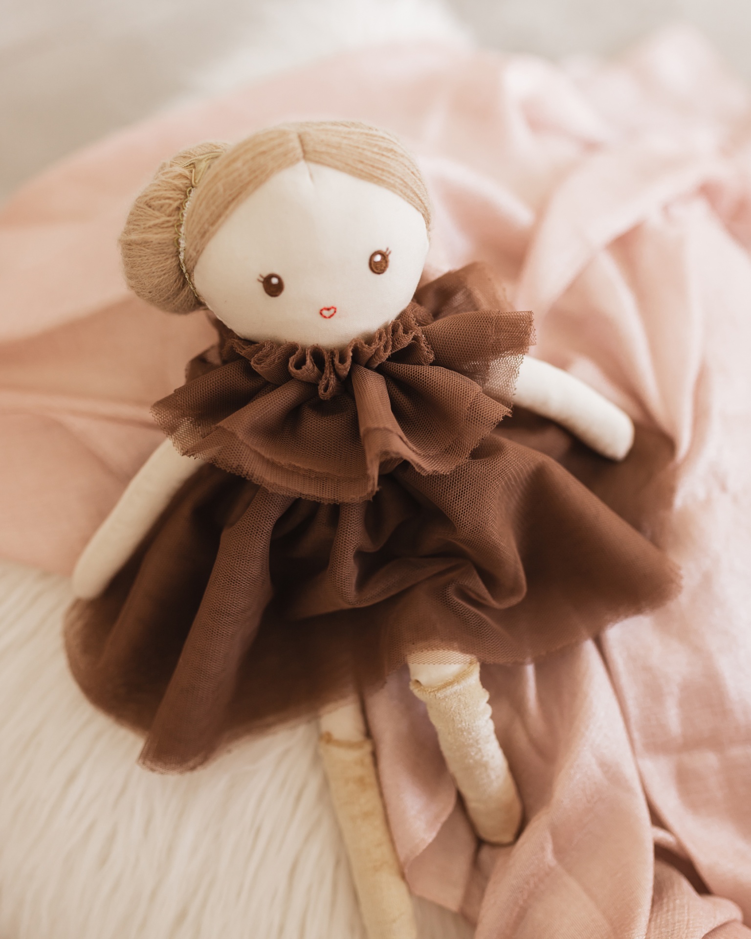 Boneca de tecido com vestido castanho em tecido macio sobre pano cor-de-rosa