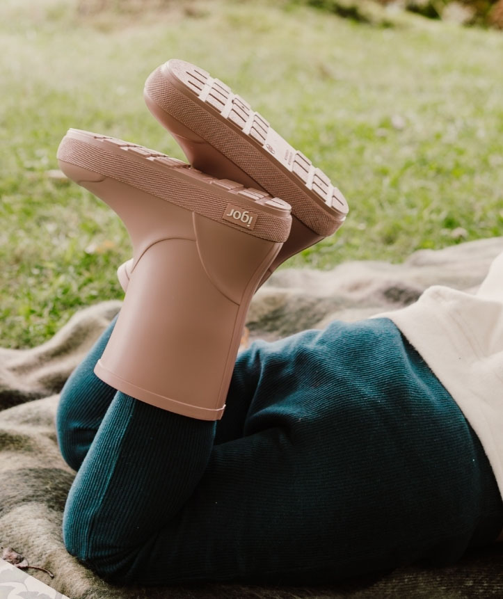 Botas de borracha castanha clara com sola texturada e marca Igor, usadas por pessoa com calças verde escuro ao ar livre