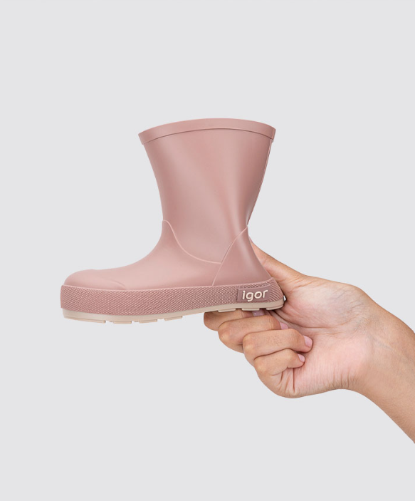 Bota de borracha rosa claro para criança segurada por uma mão