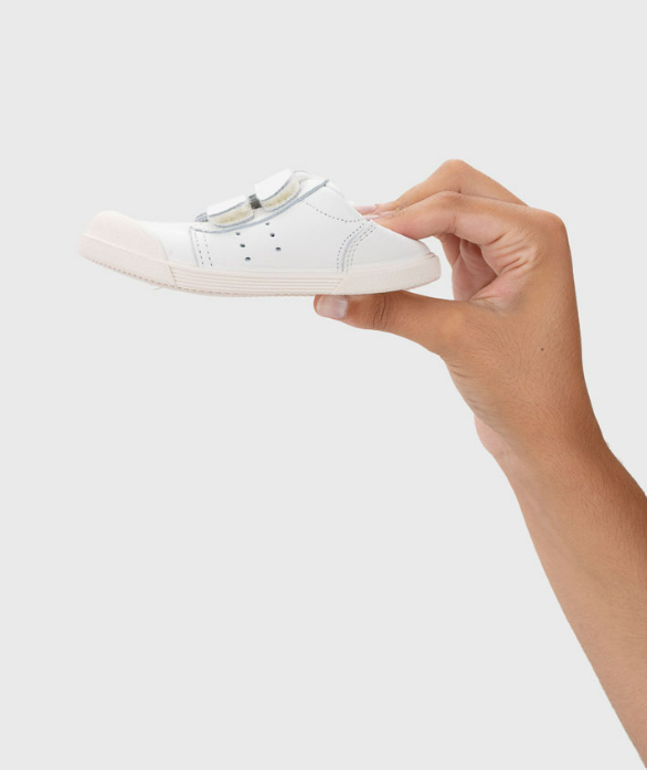Sapato infantil branco com fecho em velcro segurado por uma mão