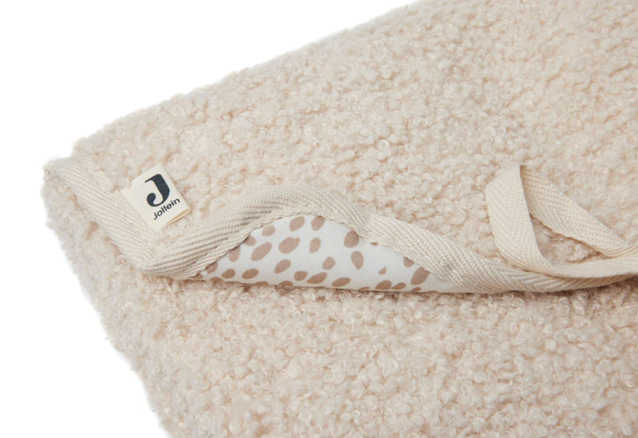 Cobertor felpudo bege claro com padrão de bolinhas castanhas no interior e etiqueta JOLLYOU