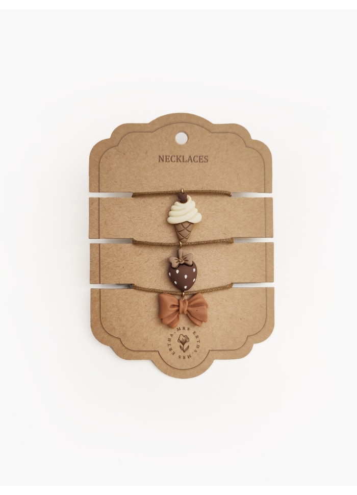 Conjunto de colares com pendentes de gelado, coração e laço sobre cartão castanho