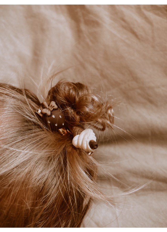 Acessórios castanhos com padrão para cabelo em cabelo loiro e fundo bege