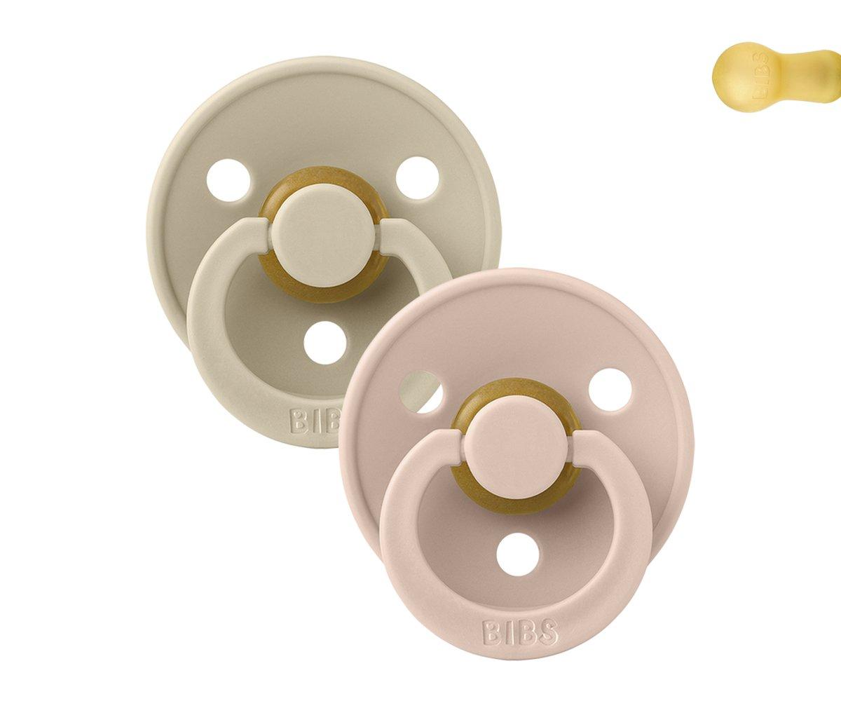 Duas chupetas BIBS redondas bege e rosa claro com anéis de silicone e botões de madeira