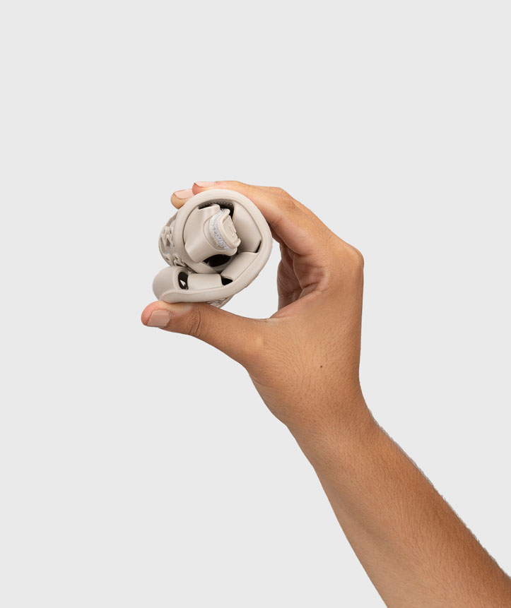 Mão segurando calçado desportivo beige dobrado