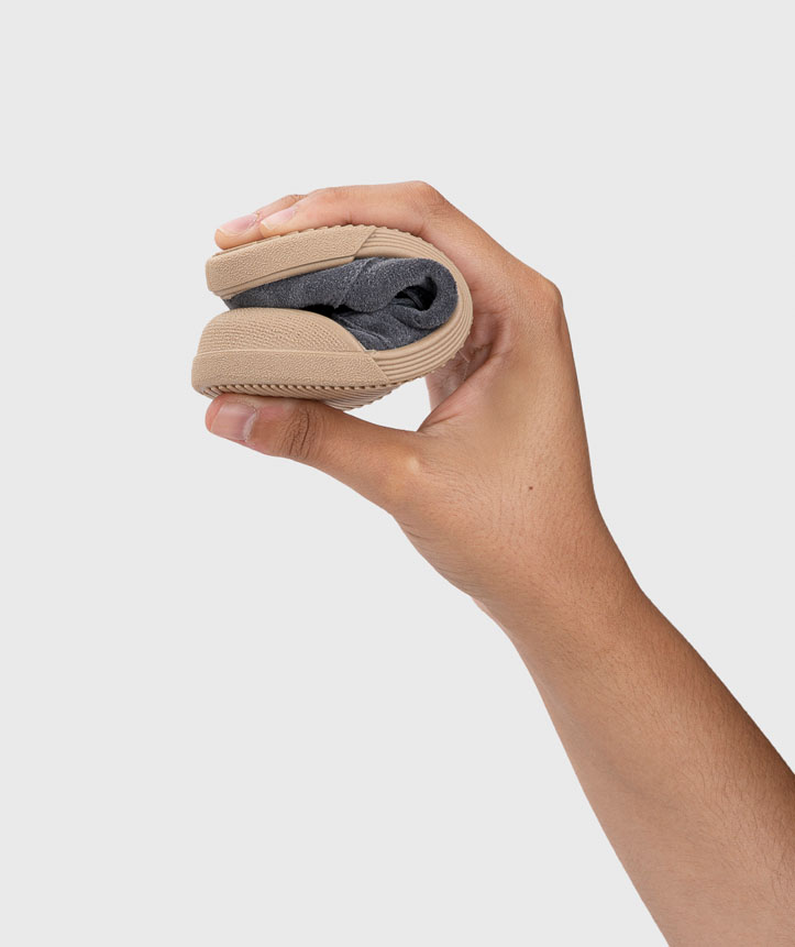 Mão segurando uma sandália dobrável bege com parte interior cinza