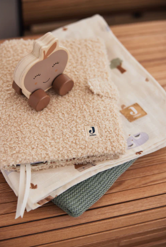 Brinquedo de madeira em forma de maçã sobre tecidos de várias texturas e cores