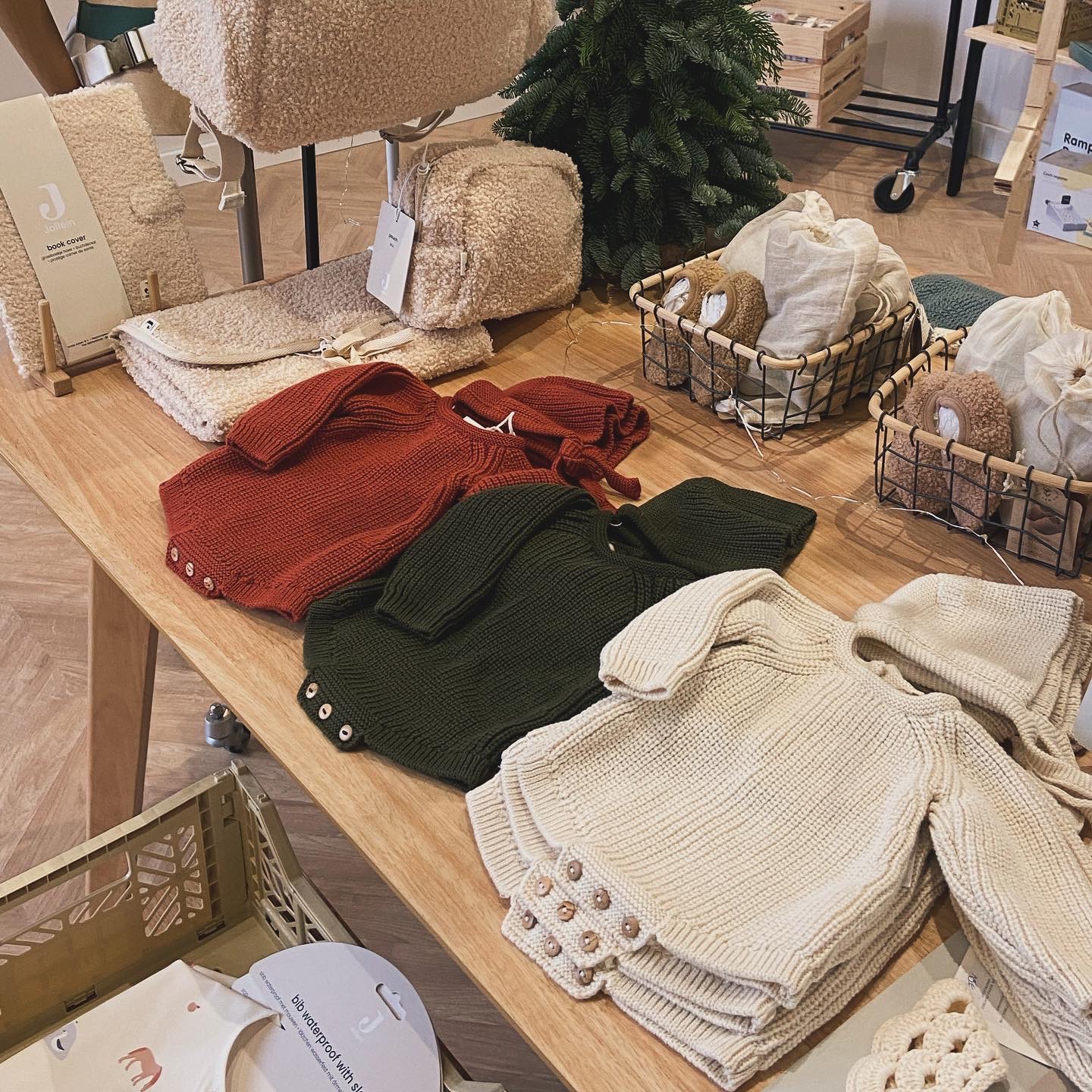 Casacos de malha para bebé em várias cores sobre mesa de madeira