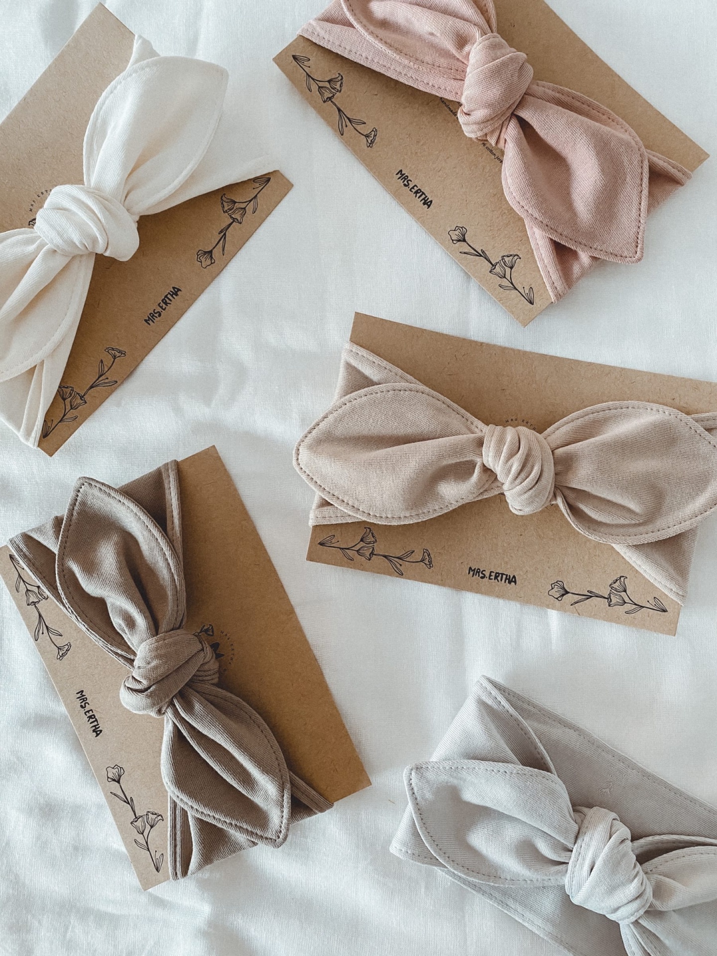 Cinco faixas de cabelo em cores neutras com rótulos de papel castanho