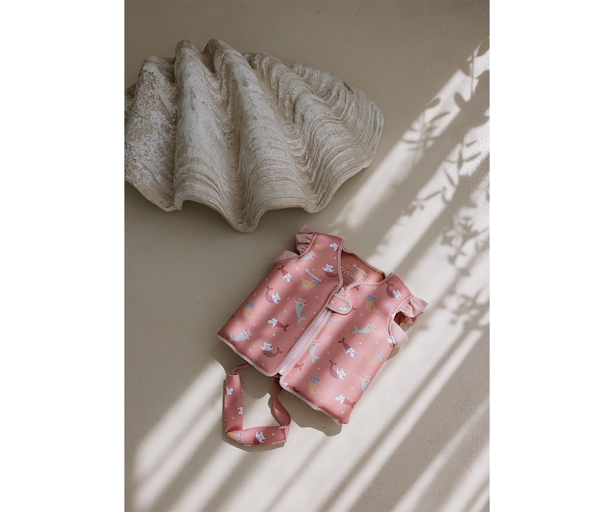 Coletes de segurança rosa com padrão de sereias, ao lado de concha decorativa clara