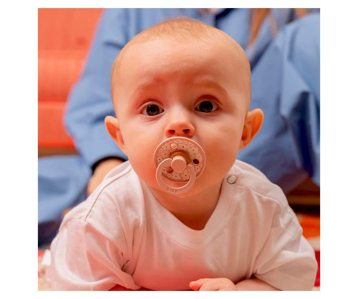 Bebé com chupeta castanha translúcida e t-shirt branca