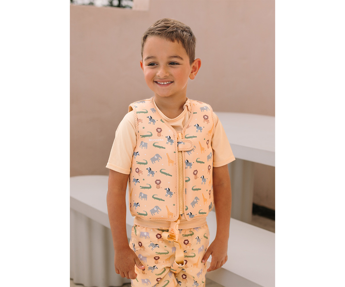 Criança com colete salva-vidas estampado e calções a combinar em ambiente exterior claro