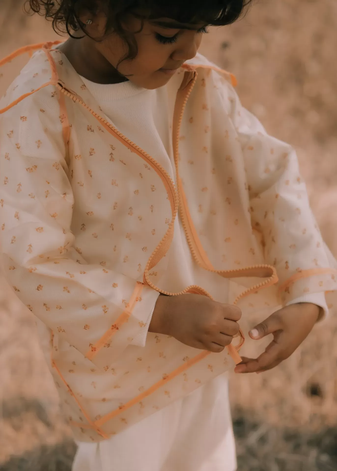 Casaco transparente infantil com padrão floral e bordas laranja